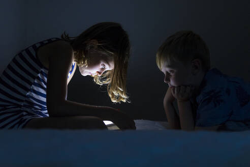 Bruder und Schwester beobachten digitales Tablet - JOHF03690