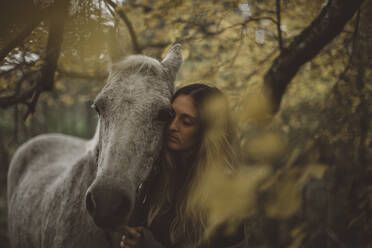 Young woman with horse in forest - JOHF03964