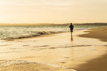 Boy running on beach at sunset - JOHF03977
