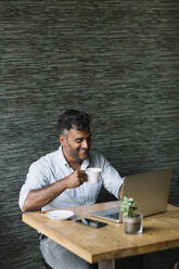 Lächelnder Geschäftsmann mit Laptop in einem Cafe - ALBF01165