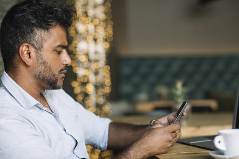 Lässiger Geschäftsmann benutzt Handy in einem Café - ALBF01170