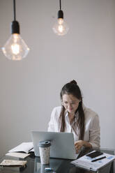 Young woman working at table in office using laptop - ALBF01182