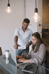 Businessman talking to employee at table in office - ALBF01184