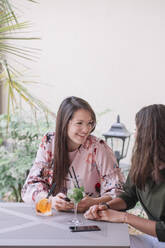 Two happy young women sitting at table with cocktails - ALBF01203