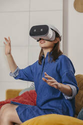 Young woman using VR glasses at home - MFF04871