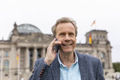Porträt eines lächelnden älteren Mannes am Telefon im Reichstagsgebäude, Berlin, Deutschland - WPEF02048