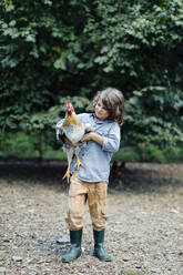 Junge hält Huhn auf einem Bio-Bauernhof - SODF00099