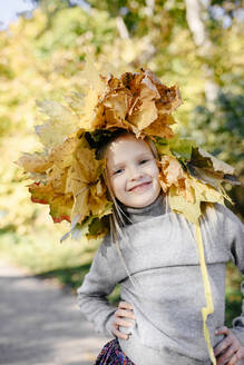 Porträt eines lächelnden kleinen Mädchens mit Herbstkranz auf dem Kopf - EYAF00590