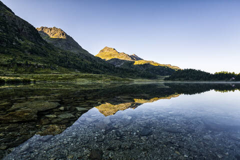 Österreich, Osttirol, Glänzender See mit Spiegelung der Berge im Defereggental, lizenzfreies Stockfoto