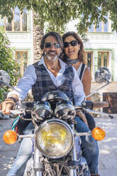 Porträt eines glücklichen reifen Paares auf einem Oldtimer-Motorrad - DLTSF00253