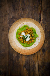Pita bread with avocado cream, turmeric, chick-peas, yogurt and parsley served on palm leaf plates - LVF08348