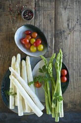 Plates and bowls with fresh cherry tomatoes, green and white asparagus, parsley, cress and pepper - ASF06506