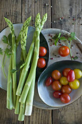 Plates and bowls with fresh cherry tomatoes, asparagus, parsley and pepper - ASF06507