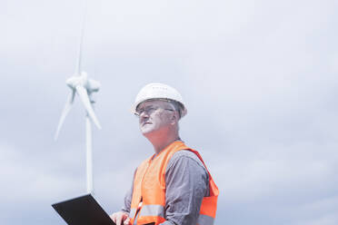 Älterer Energieingenieur vor einer Windkraftanlage - CAVF65130