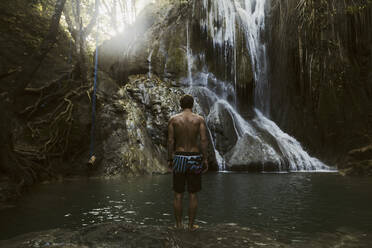 Mann steht in der Nähe eines Wasserfalls - CAVF65279