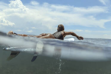 Woman lying on surfboard on the sea - CAVF65288