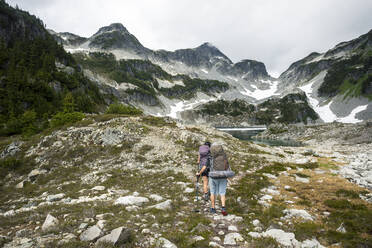 A couple hikes along a trail for a night of camping in the mountains. - CAVF65290