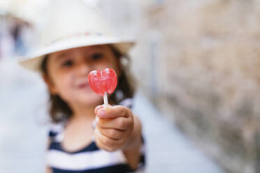 Little girl's hand holding heart-shaped lollipop, close-up - GEMF03212