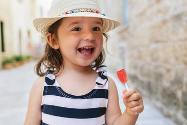 Portrait of happy little girl with red lollipop in summer - GEMF03215