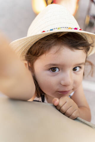 Portrait of little girl with brown hair and eyes wearing straw hat stock photo