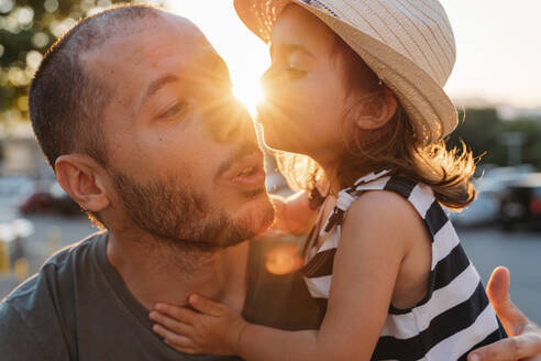Kleines Mädchen küsst ihren Vater bei Sonnenuntergang - GEMF03224