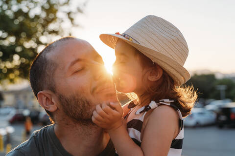 Kleines Mädchen küsst ihren Vater bei Sonnenuntergang, lizenzfreies Stockfoto