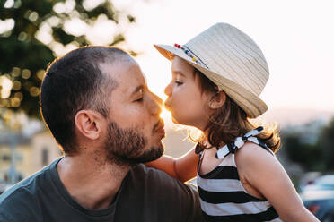 Kleines Mädchen küsst ihren Vater bei Sonnenuntergang - GEMF03227