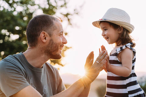 Vater und kleine Tochter spielen zusammen bei Sonnenuntergang, lizenzfreies Stockfoto