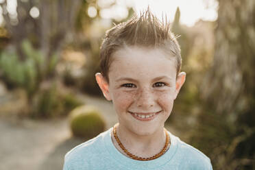 Close up Porträt von niedlichen jungen Jungen mit Sommersprossen lächelnd - CAVF65309