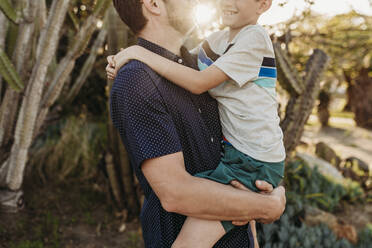 Mid view of father holding older son and smiling at each other - CAVF65320