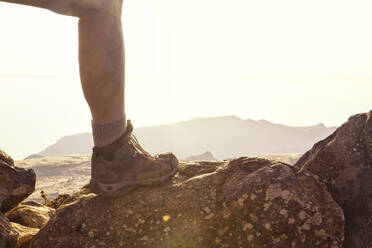 Spain, Canary Islands, La Gomera, Leg of male hiker standing on rock at Table Mountain - MAMF00874