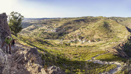 Spain, Canary Islands, La Gomera, Two hikers ascending Table Mountain with mountain village in background - MAMF00880