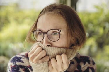 Young woman with glasses wearing fluffy sweater looking sideways - MFF04881