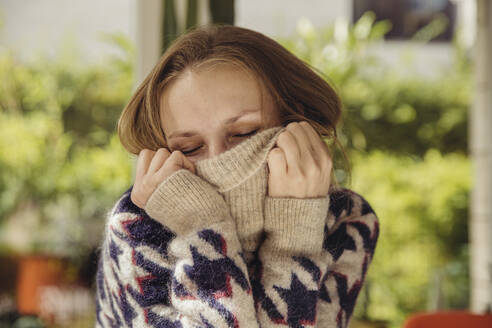 Porträt einer jungen Frau mit geschlossenen Augen, die in ihrem Wollpullover versinkt - MFF04882