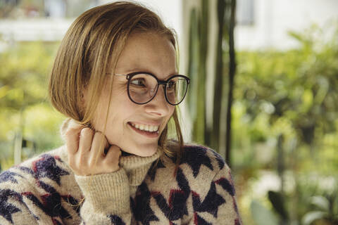 Porträt einer lächelnden jungen Frau mit Brille und flauschigem Pullover, die zur Seite schaut, lizenzfreies Stockfoto