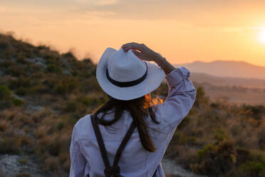 Junge Frau geht mit Hut und Rucksack auf den Berg. Reisen, Abenteuer, Lifestyle - CAVF65381
