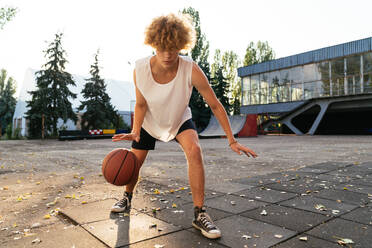 Männer mit kurvigem Haar spielen Basketball im Freien - CAVF65413
