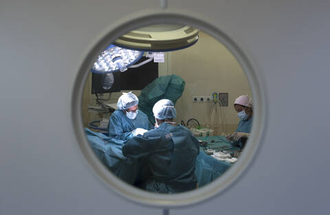 Surgeons and nurse during a surgery behind the door stock photo