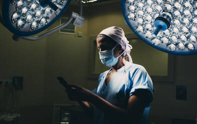 Krankenschwester benutzt ein Mobiltelefon im Operationssaal - DAMF00190
