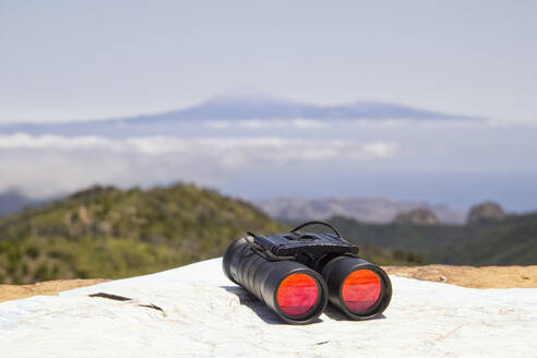 Spanien, Kanarische Inseln, La Gomera, Fernglas und Landkarte auf dem Gipfel des Garajonay mit dem Vulkan Teide in der Ferne - MAMF00893