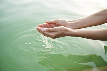 Close-up of woman's hands touching water of a lake - PNEF02206