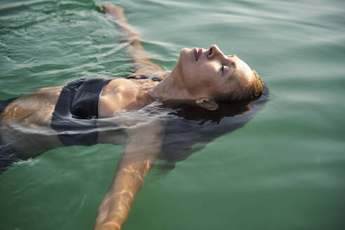 Reife Frau schwimmt mit geschlossenen Augen in einem See - PNEF02207
