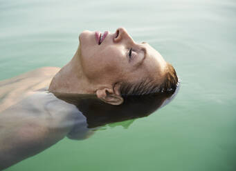 Reife Frau schwimmt mit geschlossenen Augen in einem See - PNEF02210