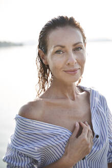 Porträt einer reifen Frau mit nassen Haaren an einem See - PNEF02218