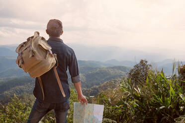 Young Man Traveler with map backpack relaxing outdoor with rocky - CAVF65485