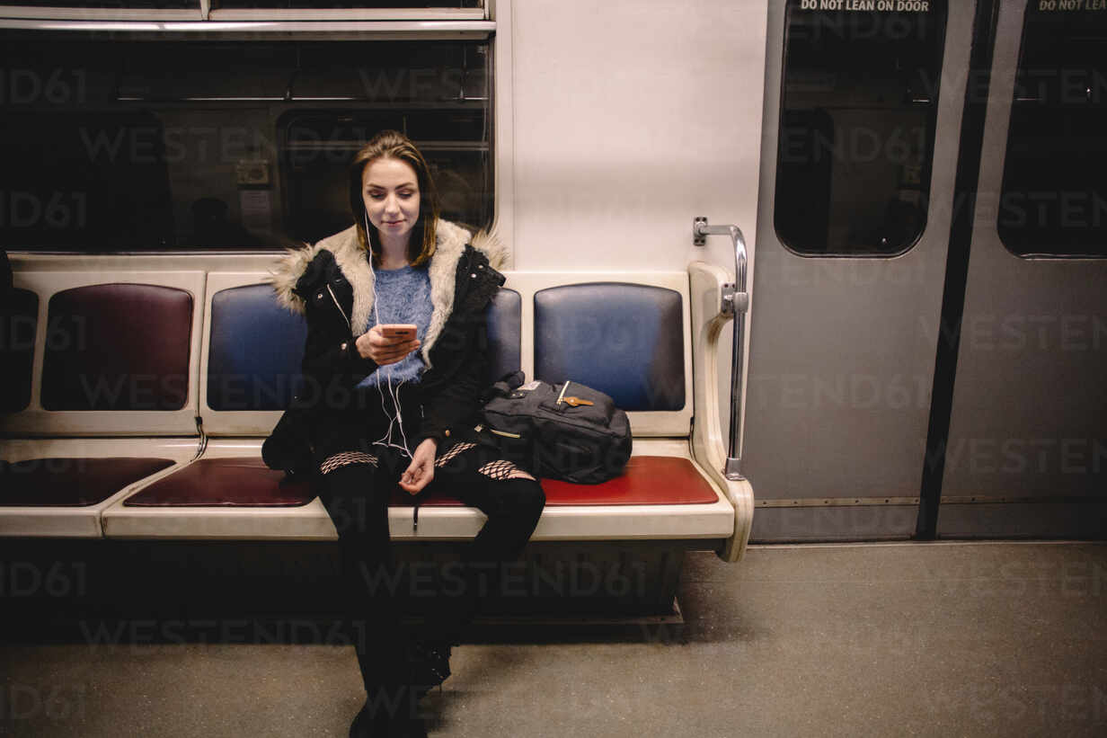 Young happy woman using smart phone while traveling in subway train stock  photo