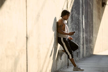 African-American man looking at phone on sidewalk - CAVF65498