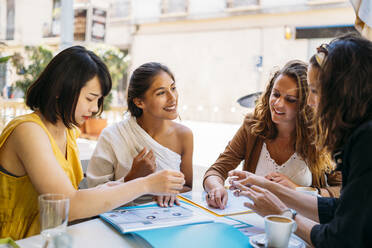 Multikulturelle Studentinnen treffen sich in einem Café und organisieren ihren Stundenplan - MPPF00099