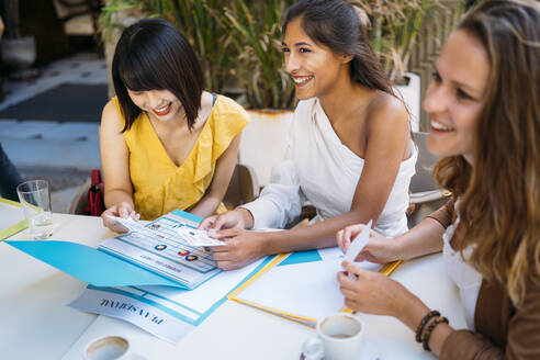 Glückliche multikulturelle Studentinnen, die sich in einem Café treffen, um ihren Stundenplan zu organisieren - MPPF00105