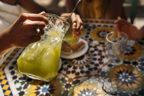 Frau serviert ihren Freunden in einem marokkanischen Café Limonade - MPPF00127